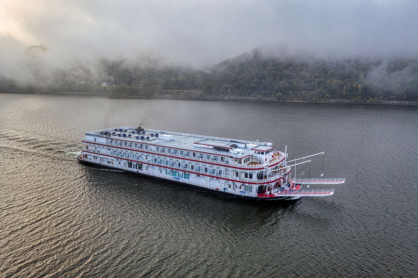 Paddlewheel steamboat sailing through morning fog on an American river, the classic image of the best USA river cruises